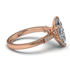 Angled view showcasing tapered pave diamond shoulders and milgrain detailing on a rose gold marquise ring.