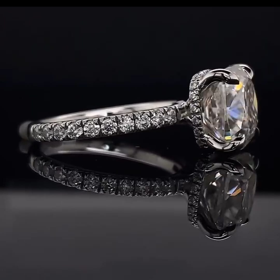 Angled side view highlighting the hidden halo collar and delicate pave diamond band of a white gold cushion cut engagement ring.