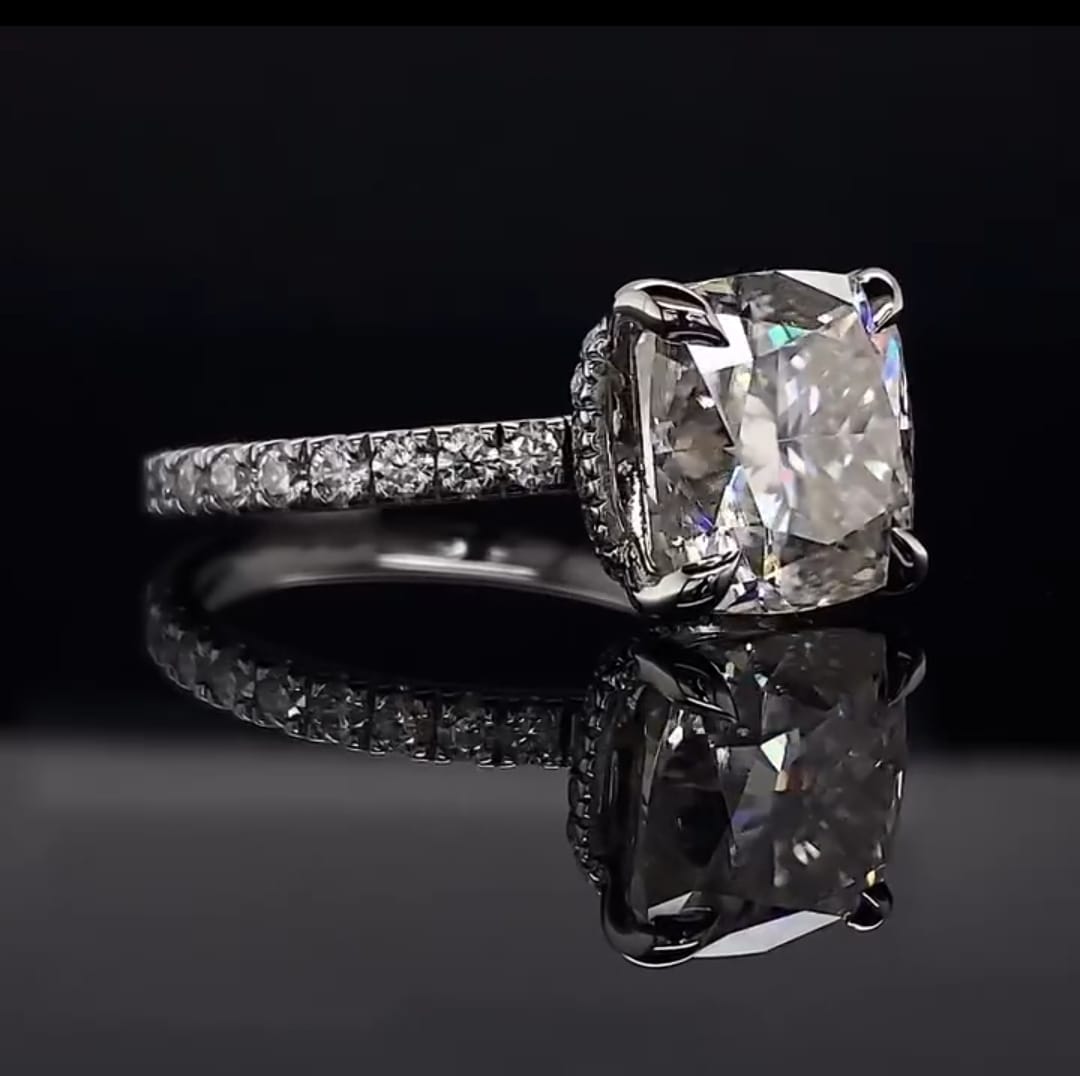 Three-quarter angle of a brilliant 3 carat cushion cut lab grown diamond engagement ring reflecting beautifully on a dark surface.