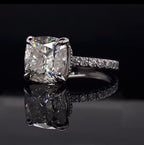 High angle view showing the soft rounded corners, elegant claw prongs, and pave band of a stunning cushion cut diamond ring.