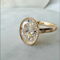 Angled front view of a 5 CT oval lab-grown diamond ring in yellow gold with a milgrain bezel frame and starburst-set accent diamonds on the band.