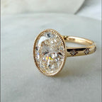 Angled front view of a 5 CT oval lab-grown diamond ring in yellow gold with a milgrain bezel frame and starburst-set accent diamonds on the band.