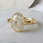 Three-quarter view of a 5 carat oval lab diamond engagement ring with vintage milgrain border and celestial star-set diamonds.