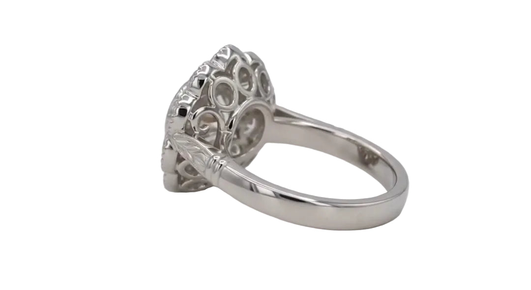 Side view of a 2 CT round lab grown diamond ring displaying an openwork scalloped gallery and engraved leaf shoulders in white gold.