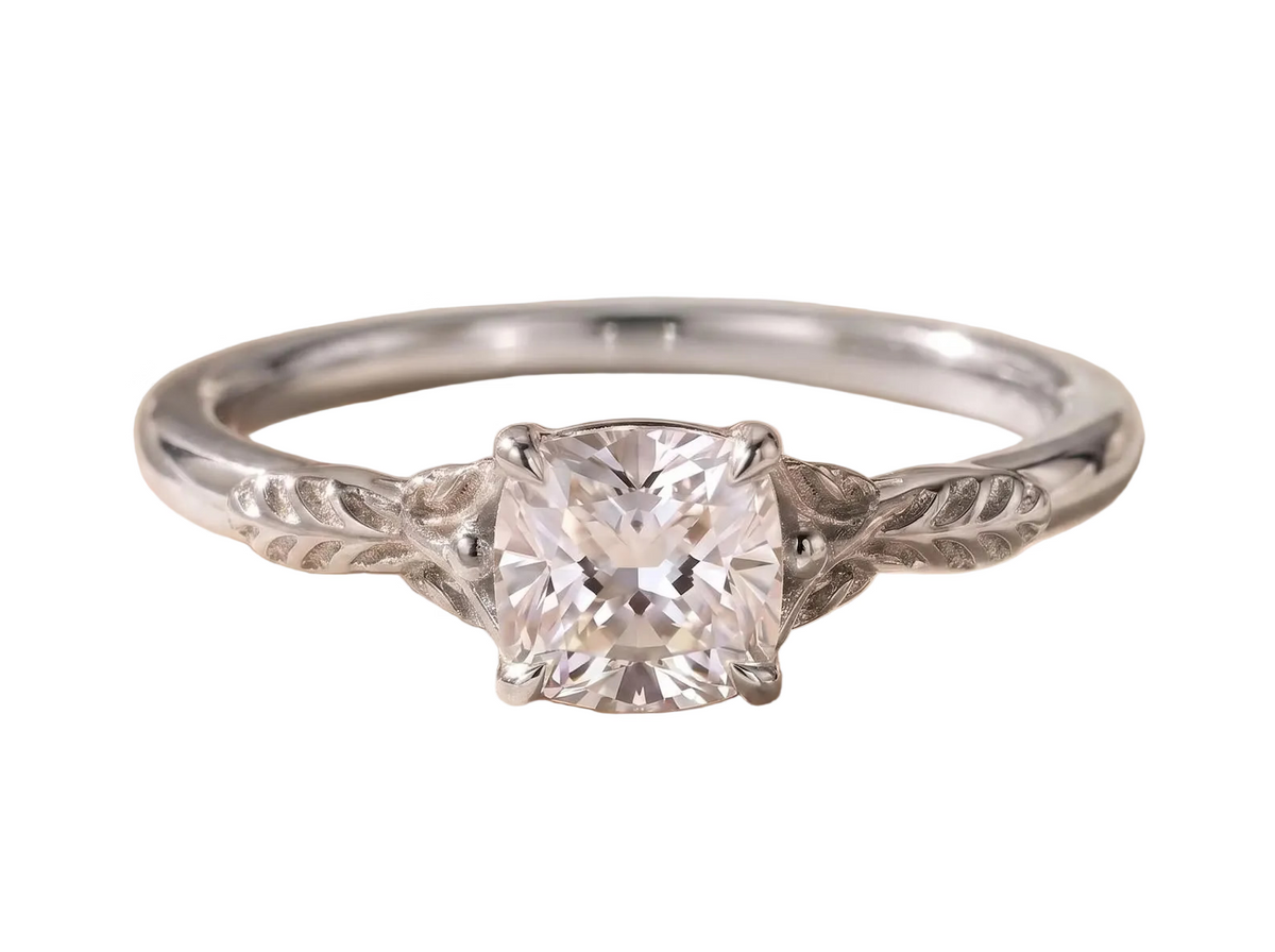 Frontal view of a 2 CT cushion cut lab diamond mounted on a white gold band with hand-carved leaf shoulder detailing.