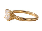 Side profile view highlighting the intricate organic leaf carvings along the yellow gold shank holding a cushion cut diamond.