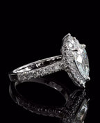 Three-quarter angled view of a teardrop diamond engagement ring showing the glowing facets and brilliant pave set shank.