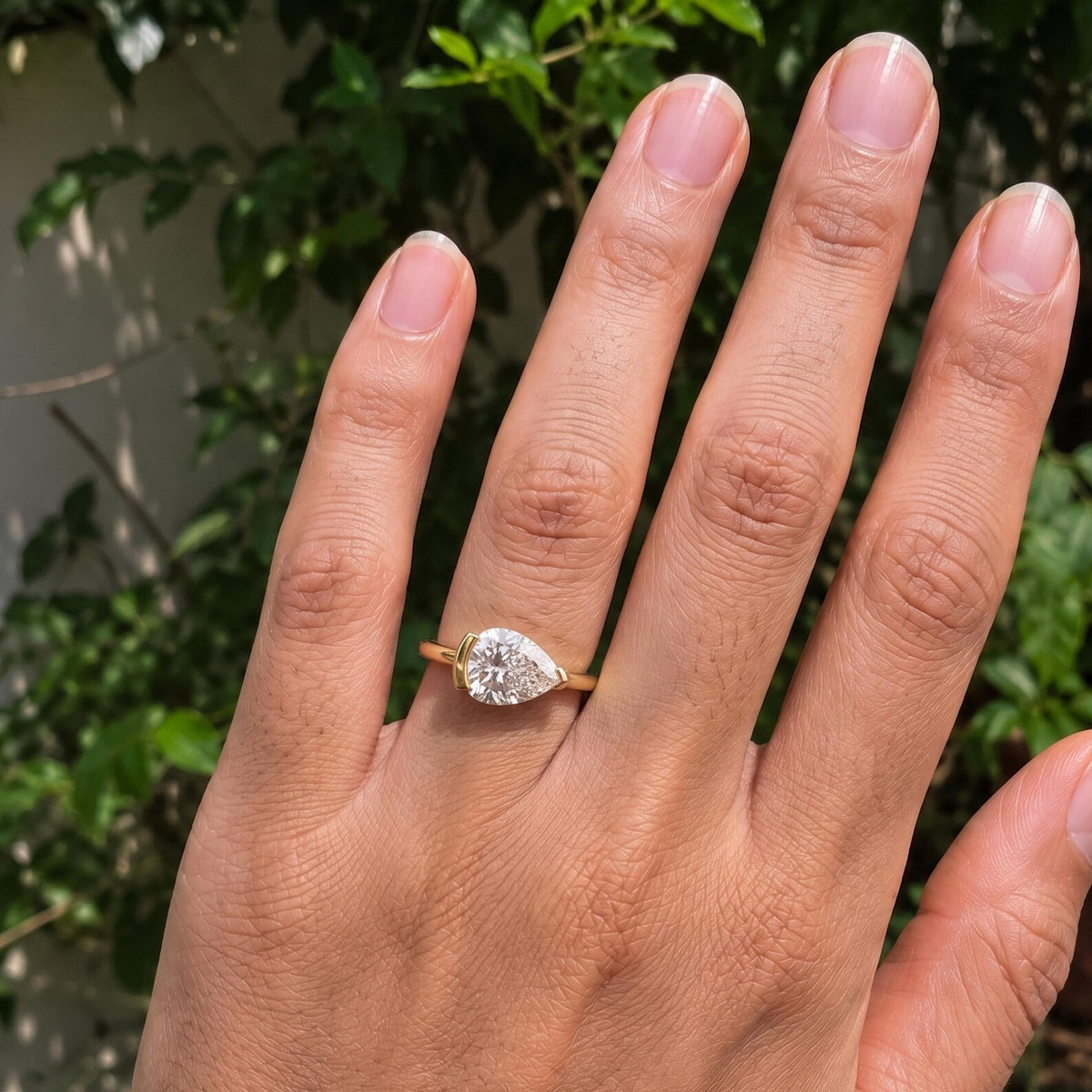Full hand view displaying a modern 2 CT East-West pear shape lab diamond ring in yellow gold.