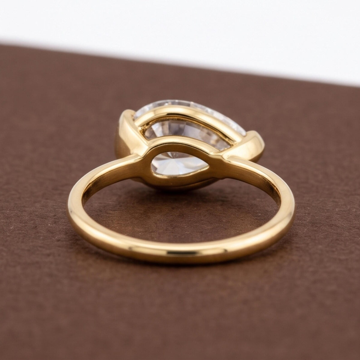 Rear structural perspective showing smooth gold band and open basket undergallery of a pear bezel ring.