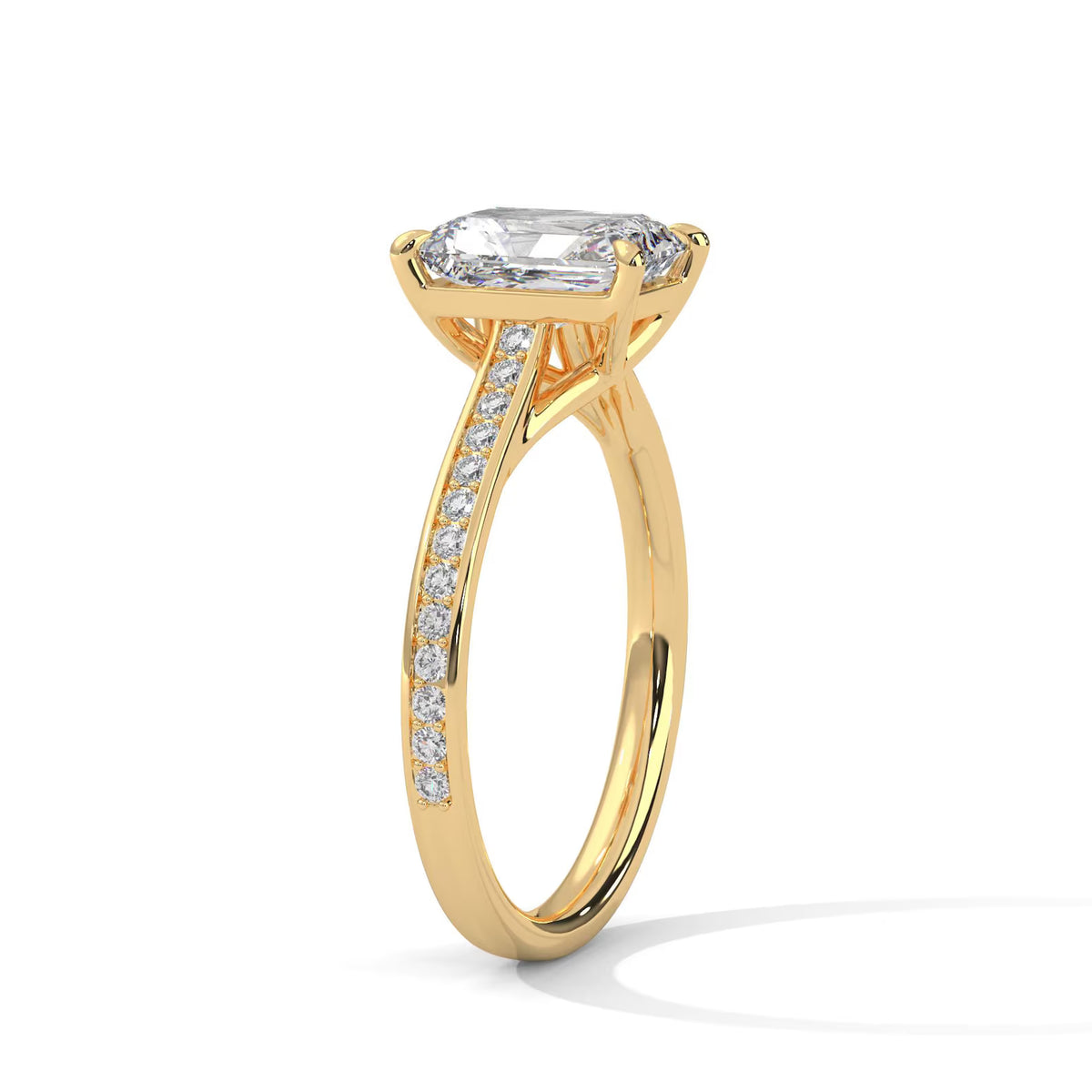 Angled perspective view of a 4 CT emerald cut lab diamond engagement ring in yellow gold with micro-pavé band.