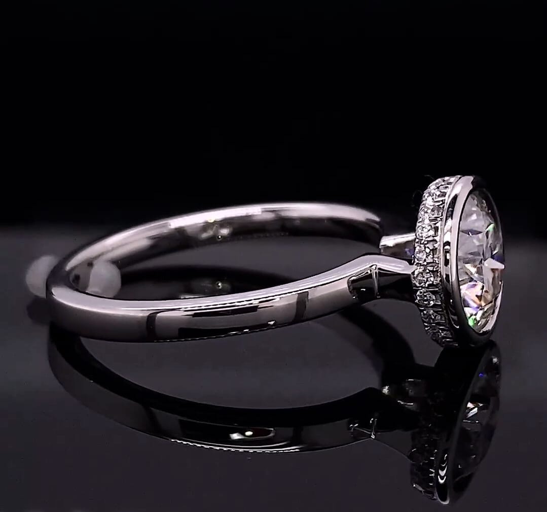 Side profile view showing the raised bezel setting and smooth shank on a reflective background