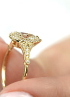 Close-up side profile showing the intricate milgrain and pavé shoulders of a yellow gold pear diamond ring