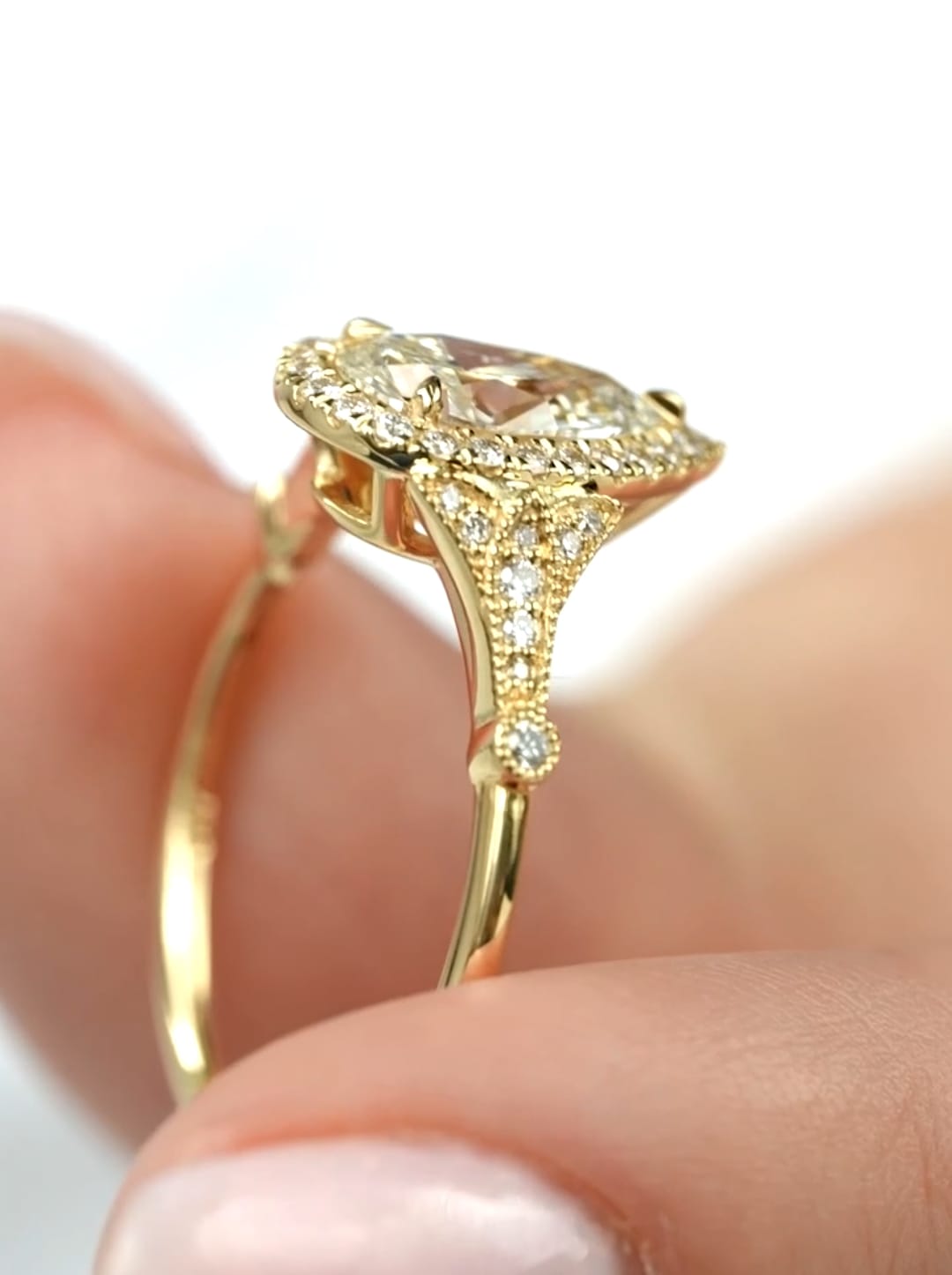 Detailed view of the vintage-inspired side shoulders and halo of a 2 CT pear lab diamond engagement ring