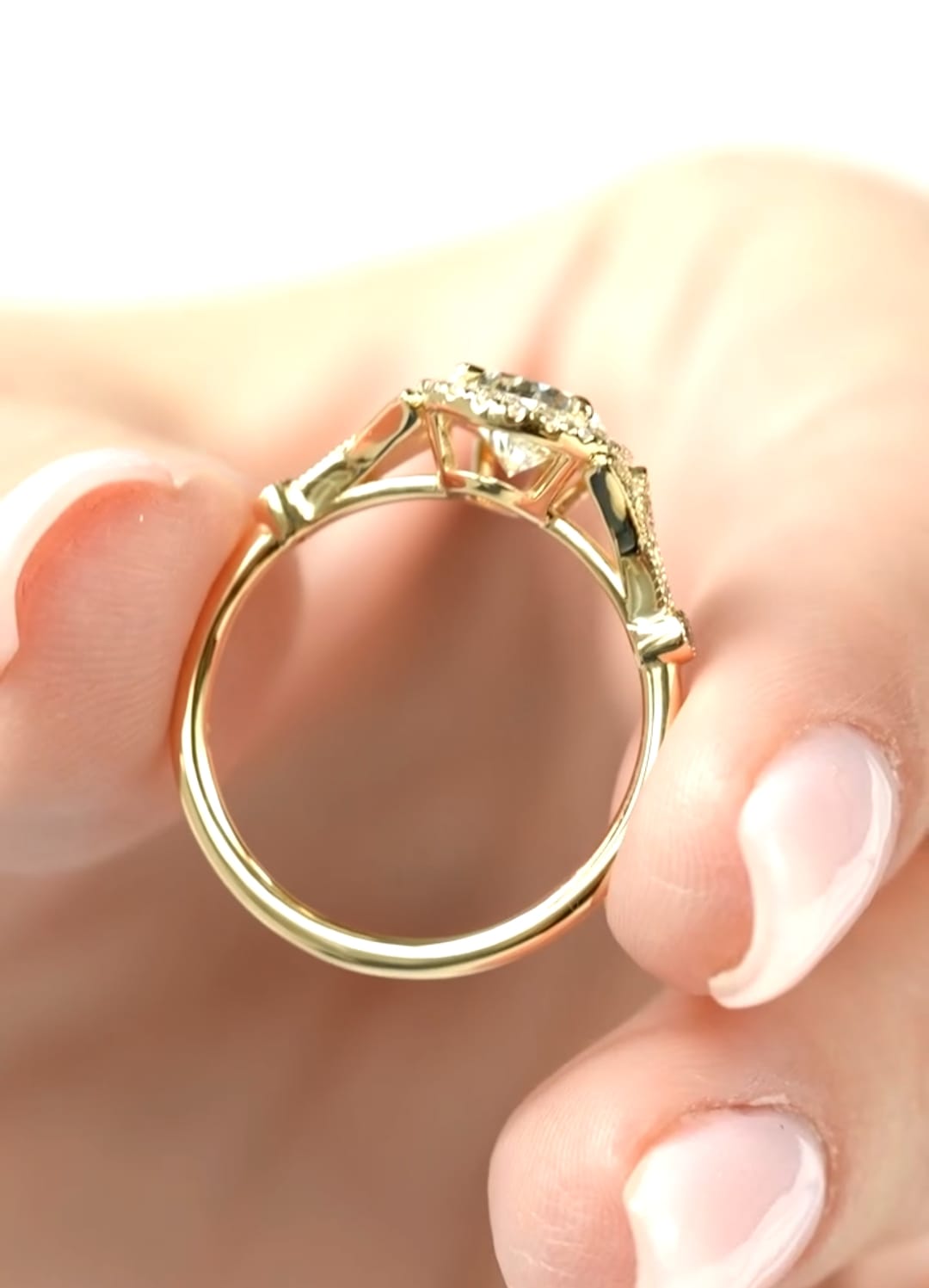 Side profile view showing the slender yellow gold band and raised halo basket setting