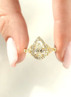 Top view held in hand displaying the 2 CT pear cut lab diamond surrounded by a halo and vintage shoulders