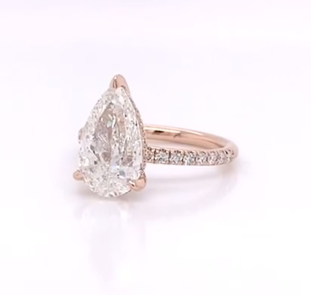 Three-quarter view of a 4 CT pear cut lab grown diamond ring with pavé band in rose gold