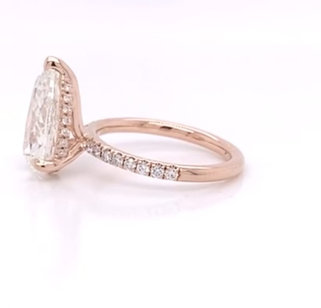 Angled side view showing the pavé setting and V-tip prong on a rose gold pear diamond ring