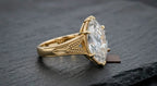 Detailed side view highlighting the intricate botanical leaf engraving and milgrain trim on the yellow gold band