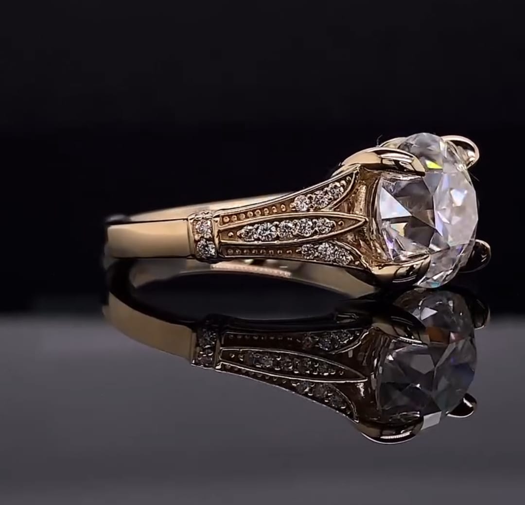 Three-quarter view of a 3 CT round lab grown diamond ring with double prongs and pavé filigree shoulders in yellow gold
