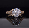 Front view showing a 3 CT round brilliant lab diamond in a double prong setting with decorated yellow gold shoulders
