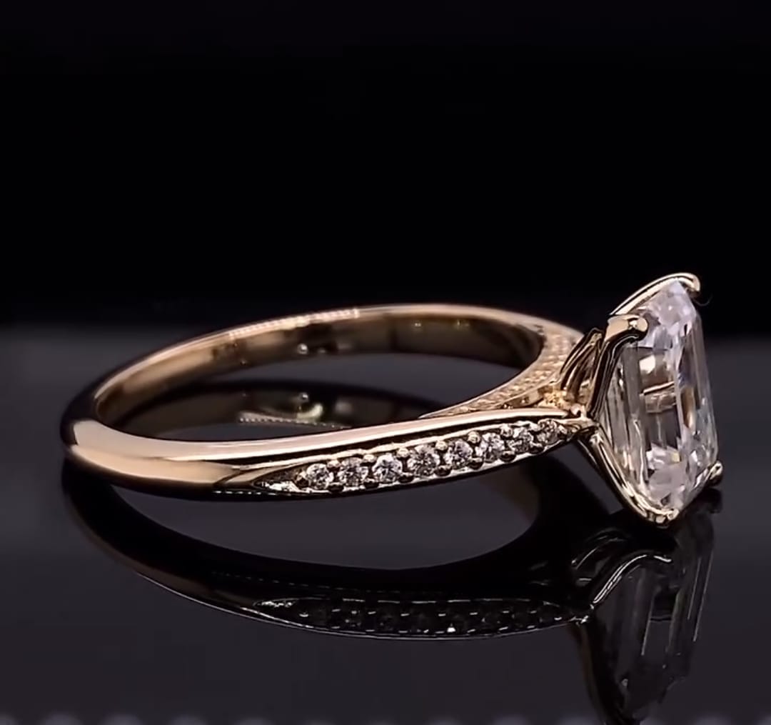 Angled view of a 3 CT emerald cut lab grown diamond ring with tapered micro-pavé shoulders in yellow gold