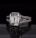 Front view of a 4 CT emerald cut lab grown diamond engagement ring with full bezel setting and split shank pave band.