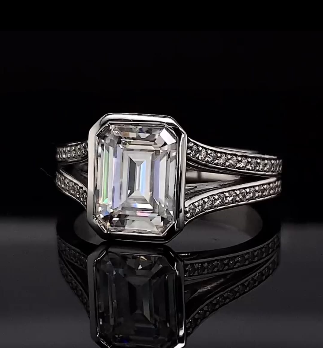 Front view of a 4 CT emerald cut lab grown diamond engagement ring with full bezel setting and split shank pave band.