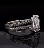 Side profile view showing the split shank pave band leading up to the bezel-set emerald cut diamond in white gold.