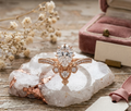 Front view of a 2 carat pear-shaped IGI certified lab diamond ring with a tiara-style crown halo setting on a decorative stone base.