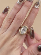 3 CT oval lab grown diamond engagement ring with a fluid, matte gold swirl bezel setting.